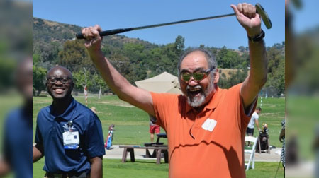 Two men golfing, one man excited holding golf club above his head