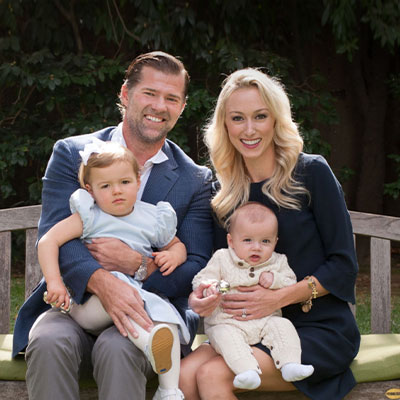 Beautiful couple sitting on a park bench with their two daughters on their laps