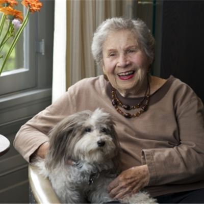 Sarah Raskin sitting on a chair with her white and gray dog
