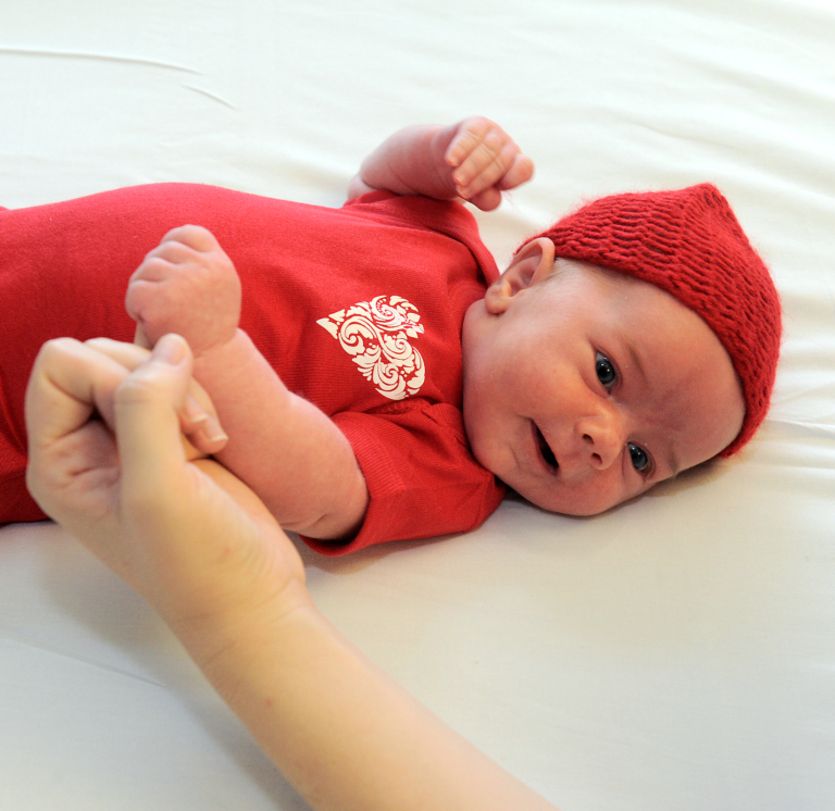 baby wearing red onesie and knit hat for heart health awareness