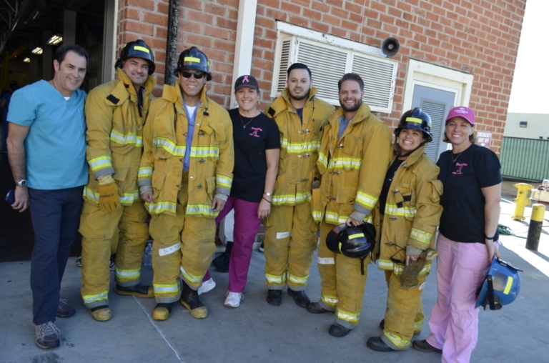 Medical staff and firefighters in turnout gear posing together outside fire station during MICN training