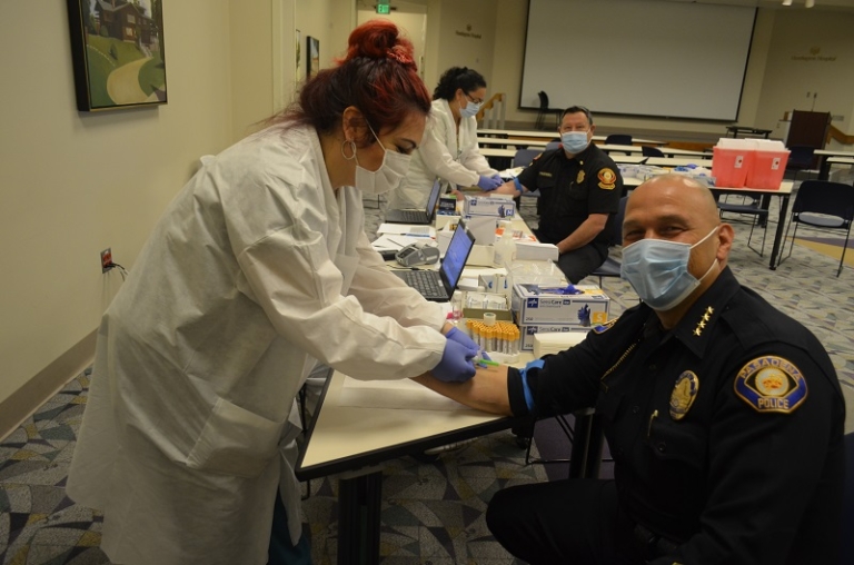 Lab technician drawing blood from masked Pasadena police officer