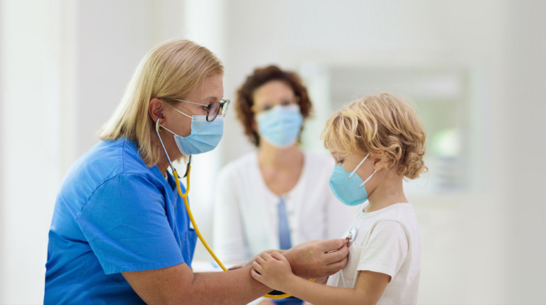 Nurse checking out child, both with face coverings on