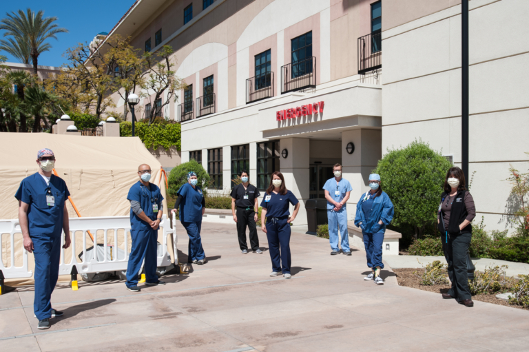 Masked healthcare workers standing outside Huntington Hospital Emergency entrance