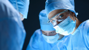 Female surgeon in mask and goggles looking up in operating room