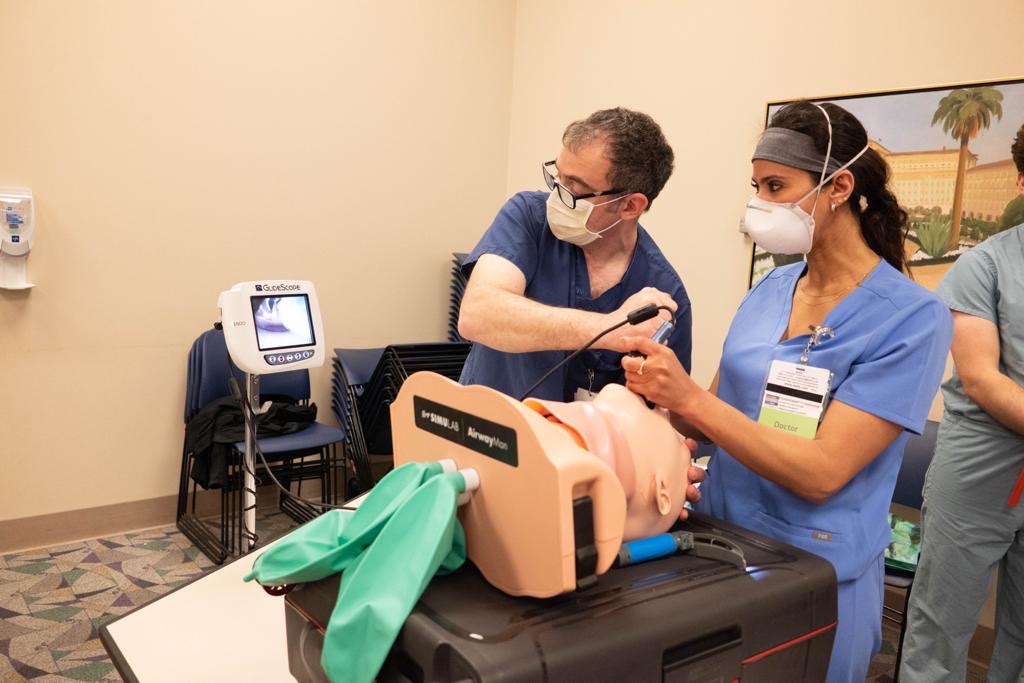 A physician and resident performing a simulated internal surgical procedure