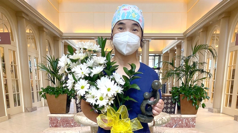 Hui-Juan-Qin-Lilly holding award and daisy flowers