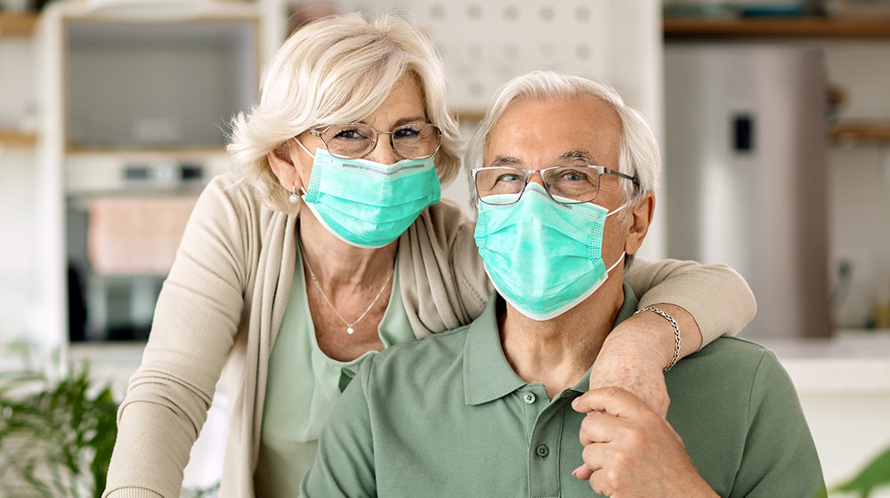 Senior couple with masks on, smiling