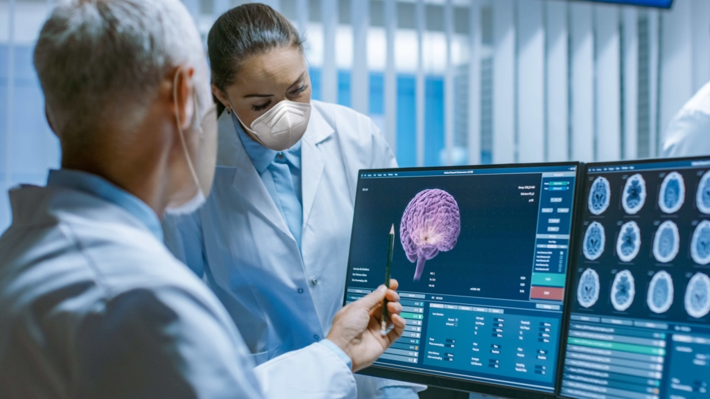 Two physicians reviewing images of brain scans. One doctor appears to be measuring an image with a pencil