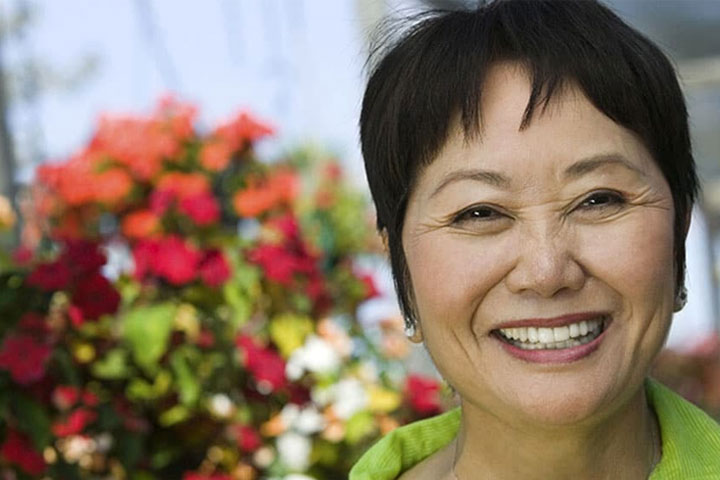 Woman smiling with flower bush in background