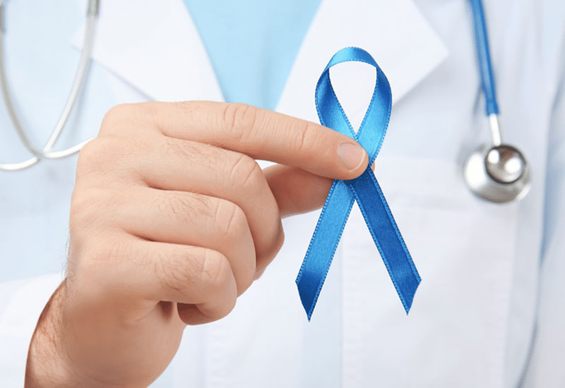 Doctor holding a blue ribbon to symbolize prostate cancer support