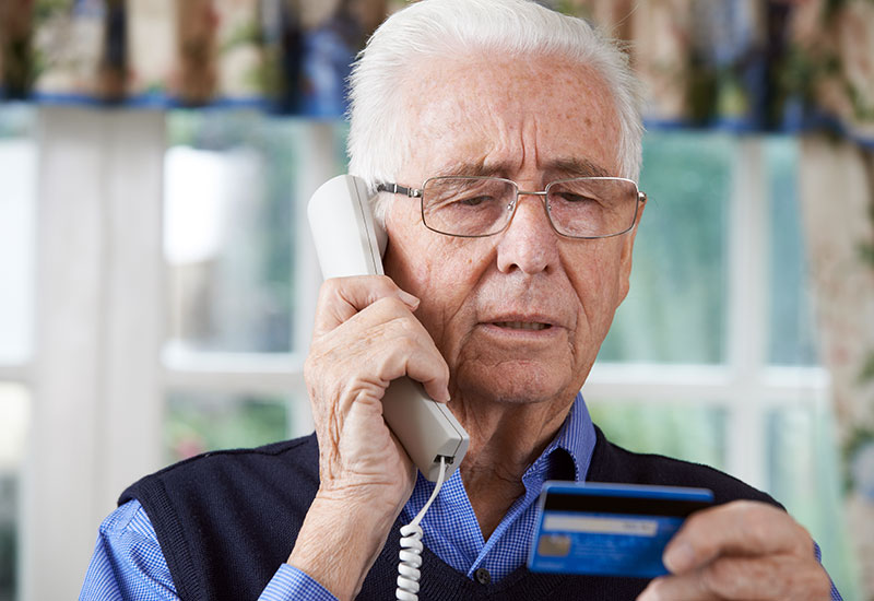 Senior man on the telephone, looking at his credit card
