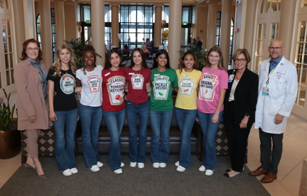 Volunteers in condiment shirts with hospital staff in lobby