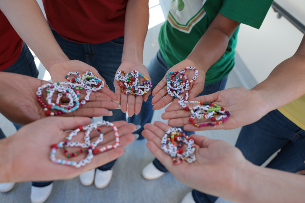 Volunteers holding colorful beaded friendship bracelets in open palms