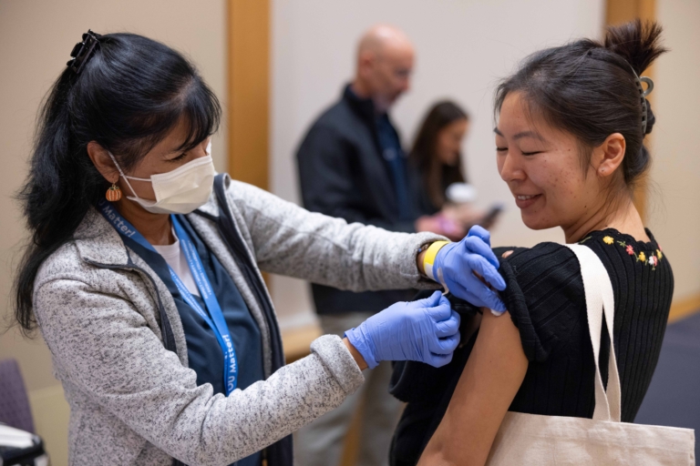Medical staff giving flu vaccine to smiling women