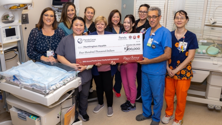 Group of professionals standing behind a Panda NICU warmer.