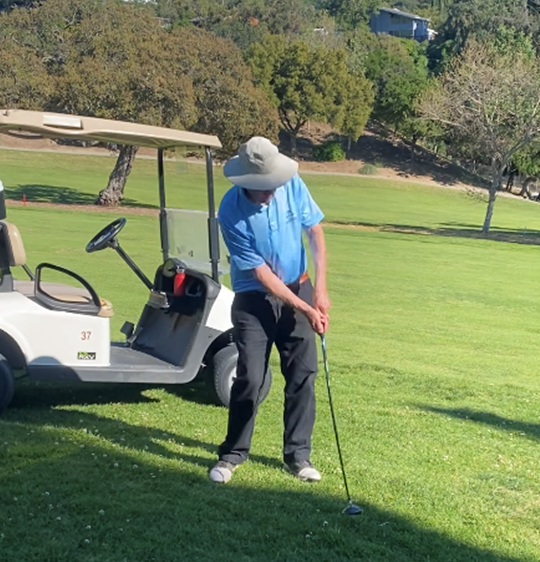 Man playing golf near cart on green course